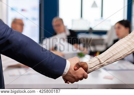 Close Up Of Multiracial Business Partners Standing In Front Of Conference Desk Shaking Hands After S