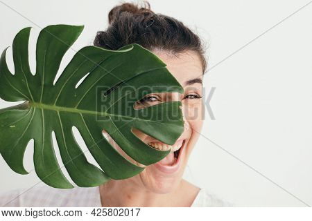 Cheerful woman with a split leaf philodendron