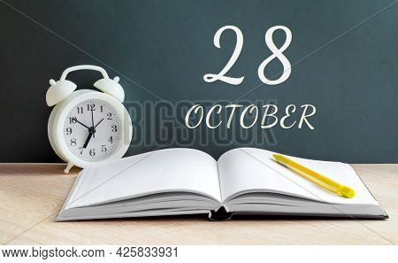 October 28. 28-th Day Of The Month, Calendar Date.a White Alarm Clock, An Open Notebook With Blank P