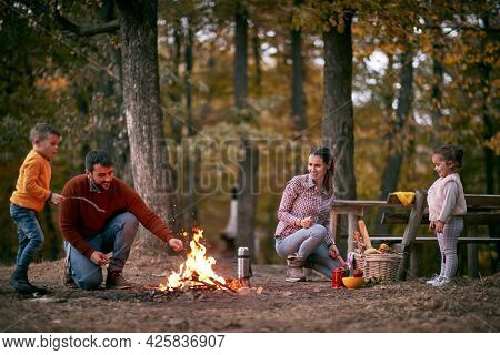 Father and son excited because of a campfire in the forest on a beautiful autumn dusk- family trip