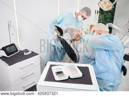 Implantology Procedure With Implant Physiodispenser. Male Dentist Using Dental Implant Machine While