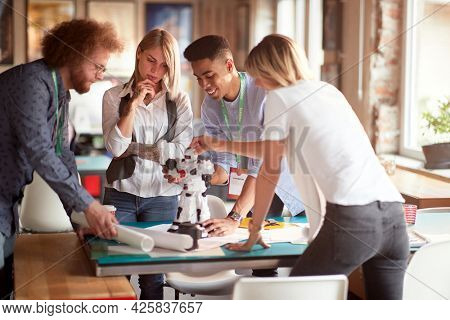 Group of young creative people is analyzing a robot toy at work in a working atmopshere in the office