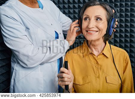 Portrait Senior Woman With White Toothy Smile While Hearing Check-up With Ent-doctor At Soundproof A