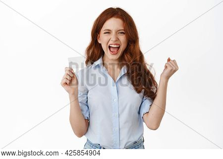 Cheerful Redhead Woman Shouting With Satisfaction, Say Yes And Show Credit Card, Ready For Shopping 