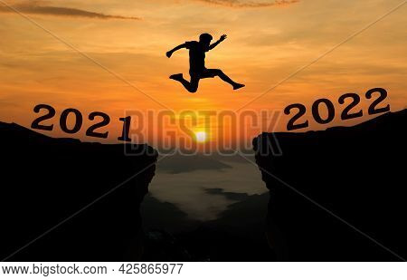 A Young Man Jump Between 2021 And 2022 Years Over The Sun And Through On The Gap Of Hill  Silhouette