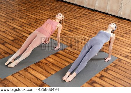 Two Women In Sportswear Practicing Yoga Asana Purvottanasana Doing The Reverse Plank