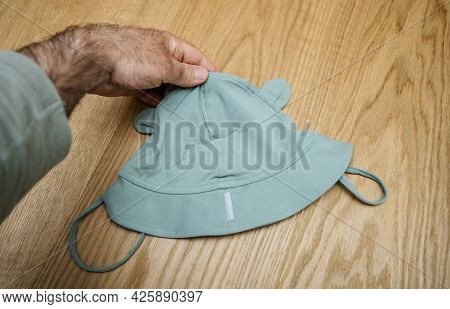 Lyon, France - May 2, 2021: Pov Male Hand Father Holding Infant Baby Cap Summer Sun Hat With Teddy A