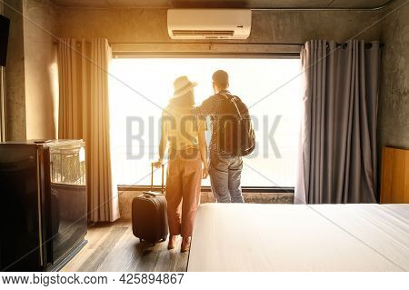 Portrait Of Young Couple Tourist Standing Nearly Window, Looking To Beautiful View Outside In Hotel/