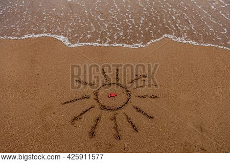 Symbol Of The Sun And A Plane By The Sea. Painted Sun On The Sand, Sea Coast, Figure Of A Red Plane,