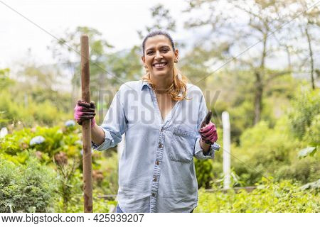 Portrait Of A Happy Woman In Her Vegetable Garden With A Shovel Stick In Her Hand