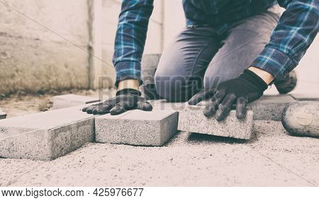 Worker lining paving slabs path