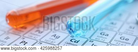Two Test Tubes With Colored Reagents Lying On Periodic Table Closeup