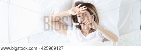 Sick Woman Lies In Bed With Thermometer Closeup