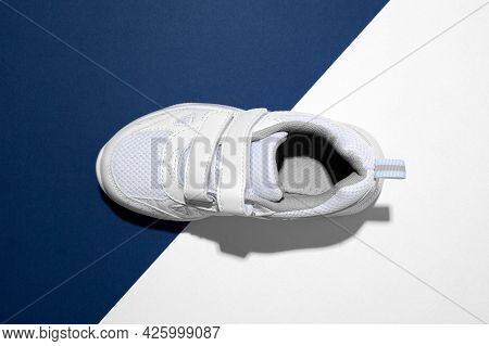 Top View Macro On One White Kid Sneaker With Velcro Fasteners For Easy Shoeing On A Trendy Blue And 