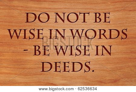 Do not be wise in words - be wise in deeds - motivational Jewish Proverb on wooden red oak background
