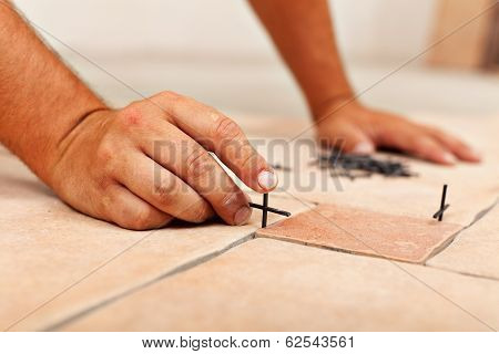 Worker Hands Placing Spacers Between Ceramic Floor Tiles
