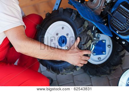 Man Mounting Tyre On A Gasoline Motor  Tiller