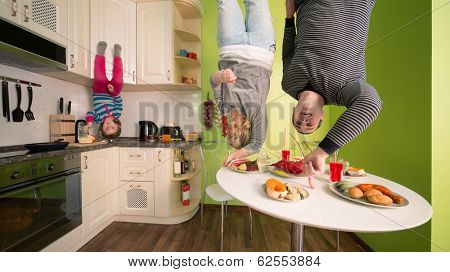 Family of three upside down in the kitchen with table and dishes
