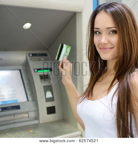 Young woman withdrawing money from credit card at ATM 