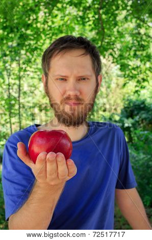 A red apple on the palm of young handsome man
