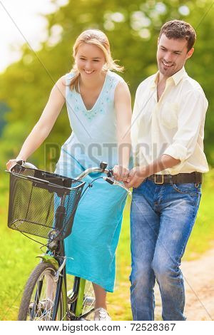 Positive And Happy Caucasian Couple Having Fun Together Riding Bike Outdoors