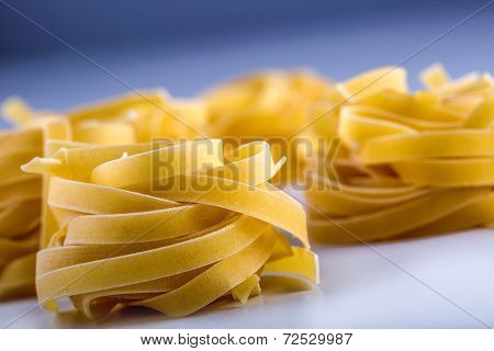 Tagliatelle pasta on white blue background.