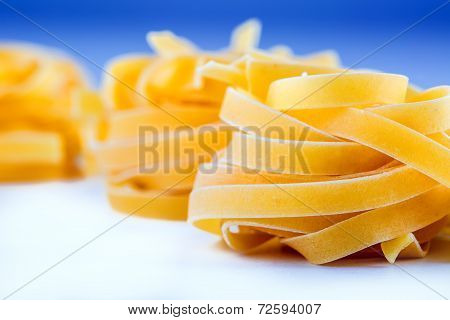 Tagliatelle pasta on white blue background.Macro concept
