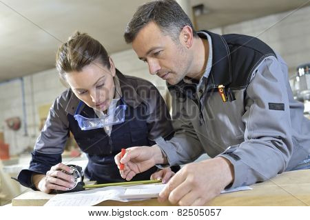 Instructor with trainee in carpentry workshop