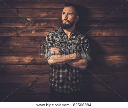 Handsome man wearing checkered  shirt in wooden rural house interior 