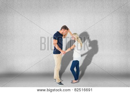 Angry man overpowering his girlfriend against grey room