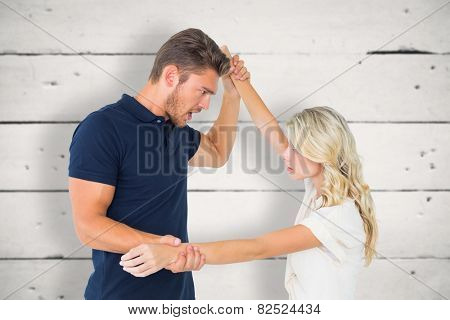 Angry man overpowering his girlfriend against white wood