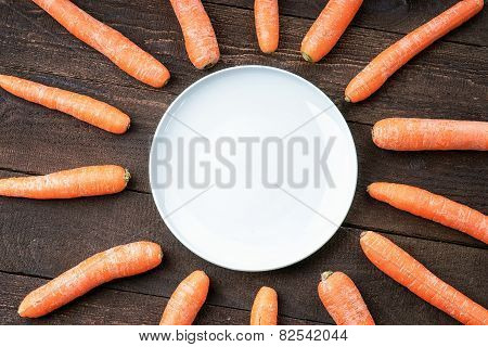 Carrots around white dish on wooden table