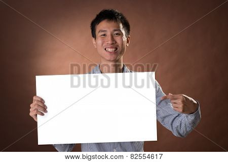 Young business guy of Chinese holding blank board in studio.