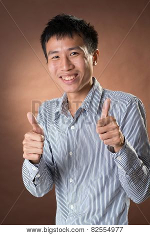 Young Chinese frank businessman give you an excellent gesture, closeup portrait in studio.