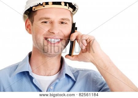 Contractor in hardhat smiles as he talks on his cell phone.