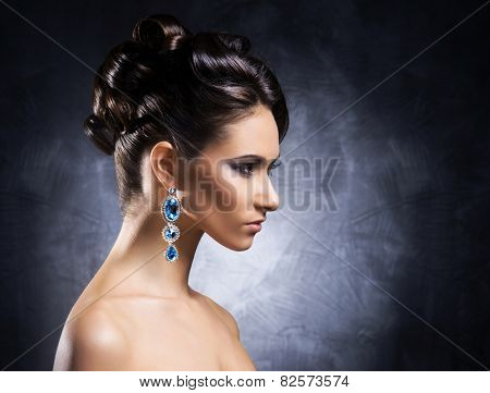 Young, beautiful and rich woman in jewels of platinum and stones over luxury background 