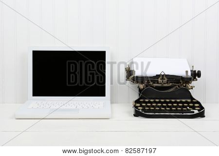Closeup of a white desk with a modern laptop computer and an antique typewriter. Horizontal format with copy space. Old vs new concept.