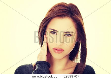 Teen woman pressing her bruised cheek with a painful expression as if she's having a terrible tooth ache.