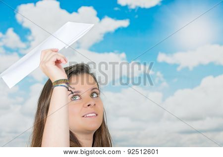 brunette holding a paperplane in front of cloud themed background