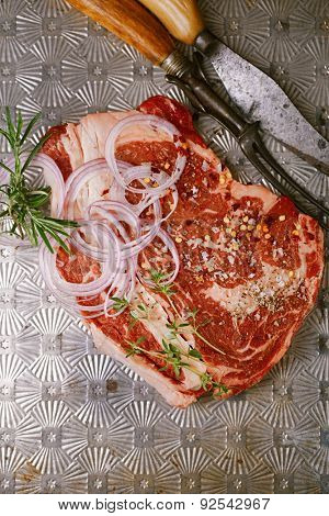 beef steak t-bone with vintage meat fork and knife on metal backdrop