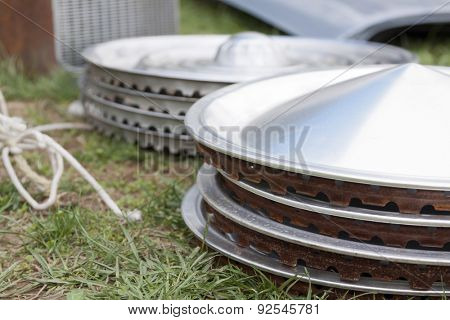 Stacks of vintage chrome hubcaps on the grass at a yard sale.