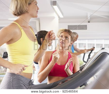 Woman On Running Machine In Gym Encouraged By Personal Trainer