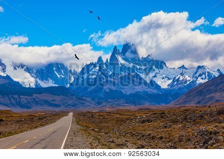 Over the road flying flock of Andean condors. The highway crosses the Patagonia and leads to snow-capped peaks of Mount Fitzroy
