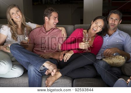 Group Of Friends Sitting On Sofa Watching TV Together