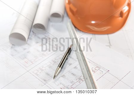 architectural plans project drawing and pen with blueprints rolls ruler and orange helmet architect engineering and contractor concept