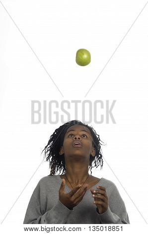 Teenage girl jugglery an apple on white background