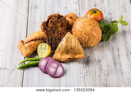 coriander vada or kothimbir vada, samosa, kachori, daal vada on brown wooden planks. indian assorted snacks. Indian snacks combination. Indian snacks group, indian favourite snacks, asian spicy snacks