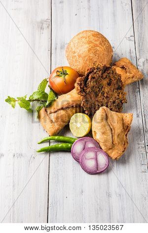 coriander vada or kothimbir vada, samosa, kachori, daal vada on brown wooden planks. indian assorted snacks. Indian snacks combination. Indian snacks group, indian favourite snacks, asian spicy snacks