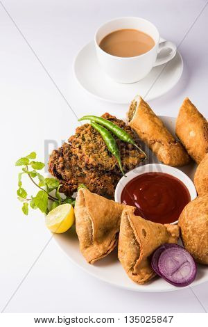 coriander vada or kothimbir vada, samosa, kachori, daal vada on brown wooden planks. indian assorted snacks. Indian snacks combination. Indian snacks group, indian favourite snacks, asian spicy snacks