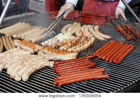 Chef cooking at barbecue big grill outdoors. Roasted pork bratwurst german sausages, white polish kielbasa. Street food